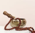 Copper singing bowl and wooden clapper on a white table. Musical instrument for meditation, relaxation, various medical practices