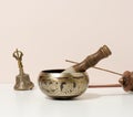 Copper singing bowl and wooden clapper on a white table. Musical instrument for meditation, relaxation, various medical practices