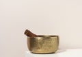 Copper singing bowl and wooden clapper on a white table. Musical instrument for meditation, relaxation, various medical practices