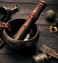 copper singing bowl and a wooden stick on a brown table