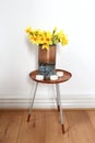 Copper vase on dipped side table with tea lights and yellow daffodils