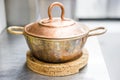 Copper vintage pot with lid on cork`s stand Royalty Free Stock Photo