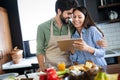 Copule in home kitchen looking at recipe on the web and cooking Royalty Free Stock Photo