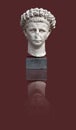 Copy of an antique sculptural portrait of the Roman emperor Claudius isolated on a red background. Design element with clipping