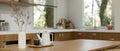 Copy space on classic wood dining table with teapot and flower vase in minimalist kitchen room