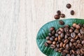 Copy space, Coffee beans on a green leaf and scattered on a light wooden table, top view, closeup grains, flat lay, place to