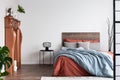 Copy space on empty white wall of rustic bedroom interior with king size bed with orange and pastel blue bedding