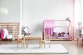 Trendy pink and bright girly bedroom with wooden furniture and toys