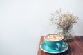 Copy space image of a blue cup of hot latte coffee and dry flowers in a vase on vintage wooden table Royalty Free Stock Photo