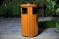 Copy space on the left. Rubbish box in the park . A wooden urn and a comfortable empty park bench at night. Yellow garbage bin