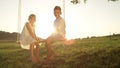 COPY SPACE LENSE FLARE Young boy and girl sitting on swing smiling at the camera