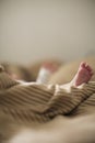 Copy space shot of a cute newborn baby foot on a brown beige blanket in bed with a bokeh blurred background Royalty Free Stock Photo