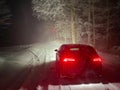 COPY SPACE: Spectacular shot of a sportscar illuminating the snowy forest road. Royalty Free Stock Photo