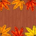 Copy space surrounded by yellow, orange and red maple leaves. Frame of fall autumn foliage on brown wooden background