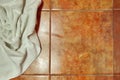 Copy space. Wet creased white towel on ceramic floor in bathroom. Ceramic tile warm colors. For background.