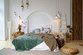 Copy space on the white blank wall of a trendy bedroom with a green and brown blanket, a double bed with many Scandi