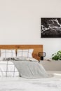 Copy space on white wall with black map in modern bedroom with king size bed with wooden headboard Royalty Free Stock Photo