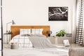 Copy space on white wall with black map in modern bedroom with king size bed with wooden headboard