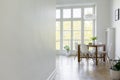 Copy space on white wall in bright dining room interior with chairs at table next to window. Real photo