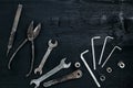 Copy space of working tools on a black wooden surface. Nippers, wrench keys, pliers, screwdriver. Top view.