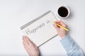 Copybook with HAPPINESS IS text. Top view of female hands writing in Notebook, cup of coffee Royalty Free Stock Photo