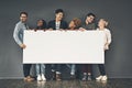 A copyspace of a diverse group of young, happy and smiling professional business people holding a blank white billboard Royalty Free Stock Photo