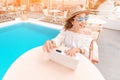 Copywriter or blogger working at a laptop on the background of the swimming pool at the resort. The concept of the modern