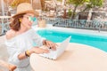 Copywriter or blogger working at a laptop on the background of the swimming pool at the resort. The concept of the modern