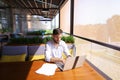 Copywriter typing text on laptop at cafe table.