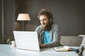 The copywriter works from home to write the article. A young man with curly hair is typing on a laptop. Work at home is Royalty Free Stock Photo