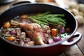 coq au vin in a rustic cast iron pot, fresh thyme garnish