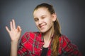 Coquettish girl showing Ok. Closeup Portrait teen smiling isolated on grey