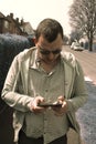 Corby, United Kingdom. April 18, 2019. Portrait of real, ordinary a man walking checking smart phone in the street. Communication