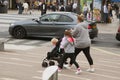 Corby, United Kingdom - august 28, 2018: Young mother walking in street with two childrens and pushchair. Active family outdoors.