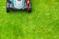 Cordless battery power lawn mower close up on green grass background Royalty Free Stock Photo