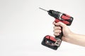 Cordless drill in black and red. Screwdriver with a drill in hand on a white background. Modern carpentry tool. Royalty Free Stock Photo