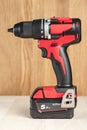 Cordless drill in black and red. A screwdriver with a drill lies on a wooden background. Modern carpentry tool close-up. Royalty Free Stock Photo