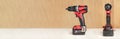 Cordless drill in black and red. A screwdriver with a drill lies on a wooden background. Modern carpentry tool close-up. Royalty Free Stock Photo