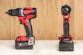 Cordless drill in black and red. A screwdriver with a drill lies on a wooden background. Modern carpentry tool close-up. Royalty Free Stock Photo