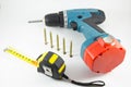 Cordless screwdriver, screws and tape measure on a white background Royalty Free Stock Photo