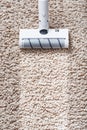 A cordless vacuum cleaner cleans the carpet in the living room with the bottom of the legs With a clean stripe Royalty Free Stock Photo