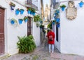 Cordoba, Spain. Beautiful girl dressed in red looking at Calleja de las flores, a famous narrow street in Cordoba, Spain during