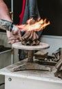 Cordoba / Spain - 2019: Local craftsman burning earthen ceramic figurine with open flame in souvenir art shop. Making statue in a Royalty Free Stock Photo