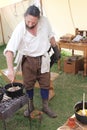 CORFE, DORSET,ENGLAND - AUGUST 06, 2015: A mediaeval re-enactor stirs an Old English recipe of pork andapple