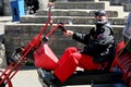 Corfe, England - June 03 2018: Mean looking biker on a chopper trike motorcycle, wearing black and red, with bandanas covering his