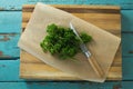 Coriander leaves, wax paper and knife on chopping board