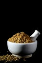 Coriander Powder and seeds with mortar and pestle on black background Royalty Free Stock Photo