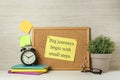 Cork board with motivational quote Big Journey Begin with Small Steps, notebooks, alarm clock and plant on white wooden table Royalty Free Stock Photo