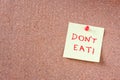 Cork board with pinned yellow note and the phrase dont eat written on it. room for text. Royalty Free Stock Photo
