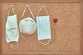 Cork board with three face masks and a bright red heart